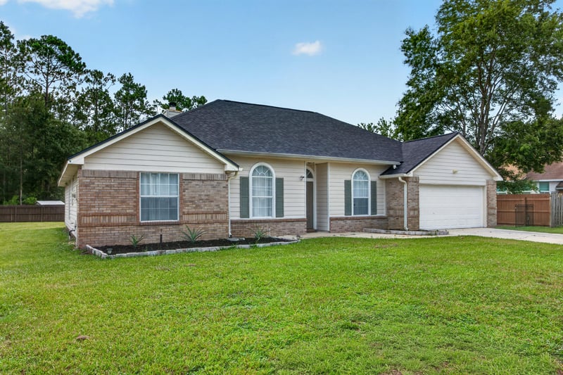 Front exterior at day-to-dusk showing arched windows and garage at 8921 Needlepoint Pl, Jacksonville, FL 32244